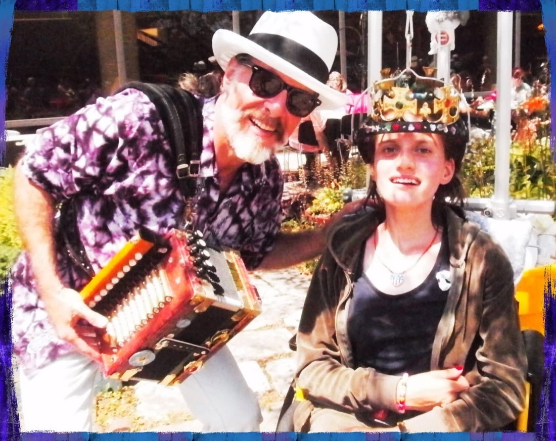 Mister Mojo playing accordion beside a young Shriners patient wearing a crown.