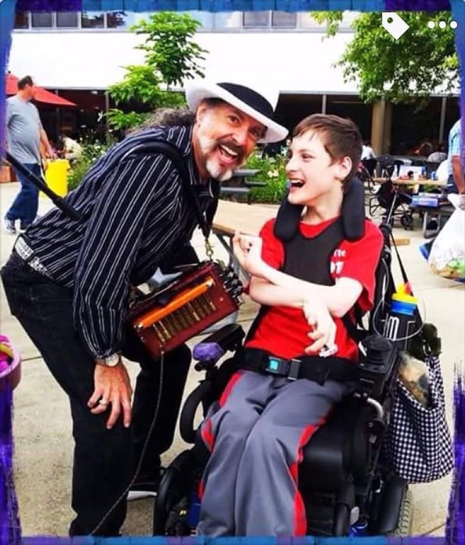 Mister Mojo sharing a laugh with a young patient in a wheelchair.